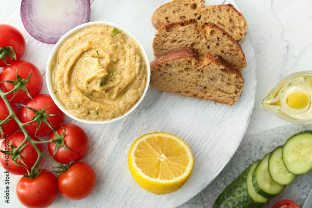 Bowl with tasty baba ghanoush, bread and fresh vegetables on light background
