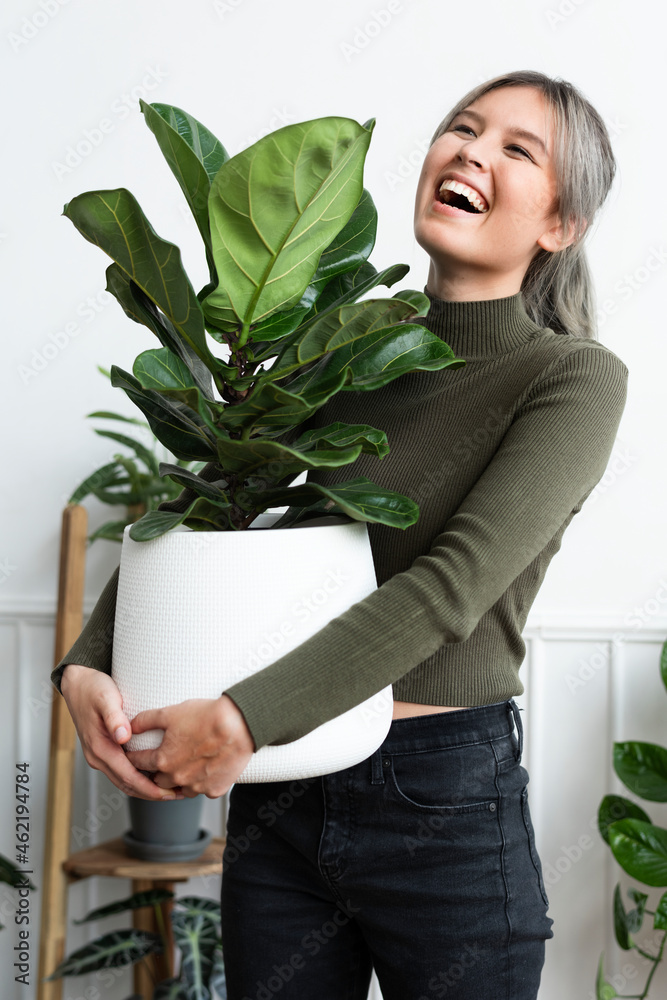 快乐的女人带着一株室内植物