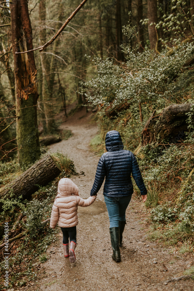 母亲和女儿在森林后视图中散步