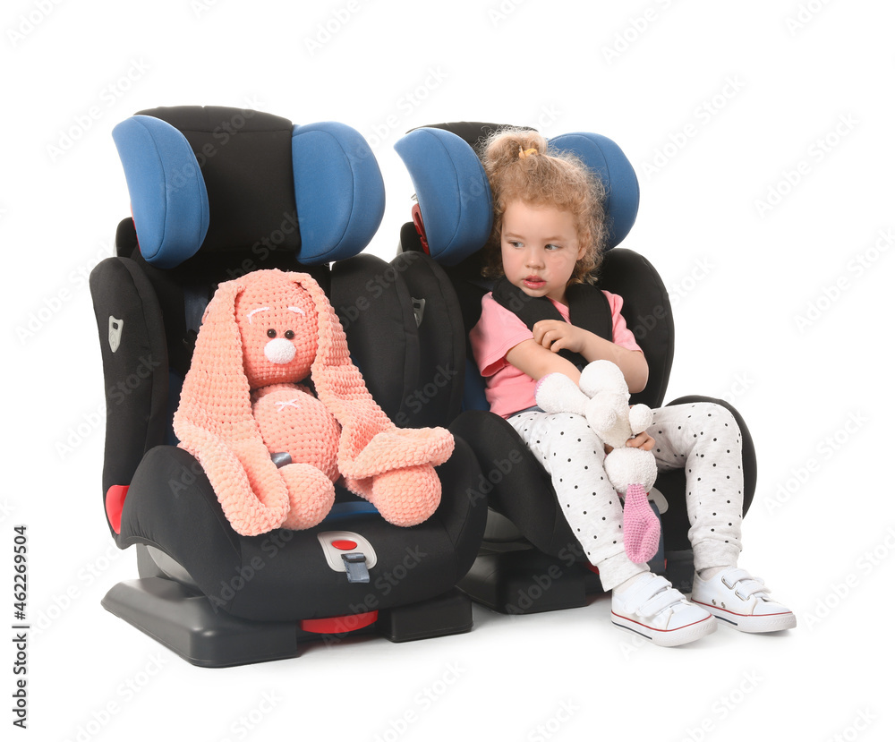 可爱的小女孩，玩具扣在白色背景的汽车安全座椅上