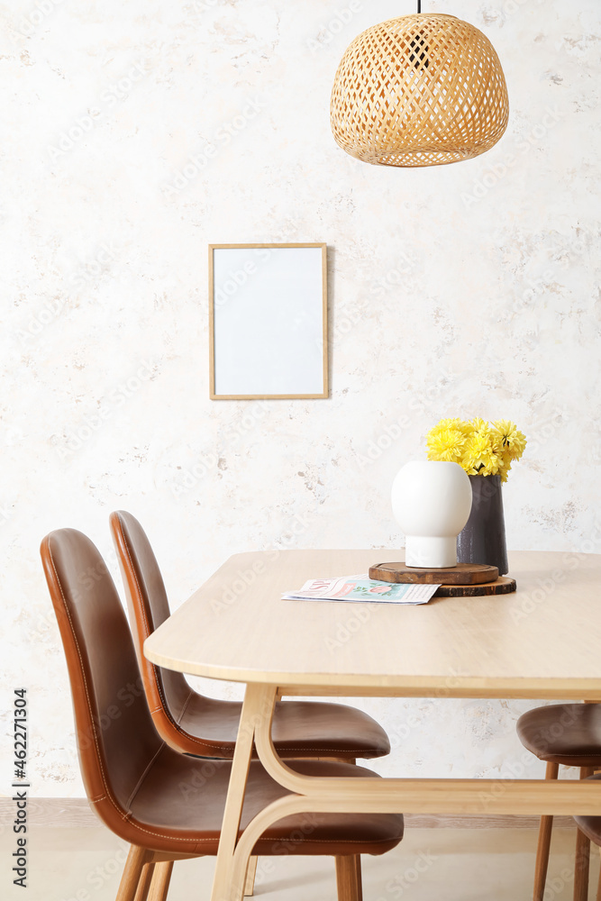 餐桌，花瓶里放着鲜花，靠近浅色墙壁的椅子