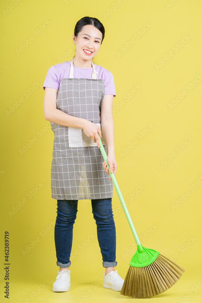 Young Asian housewife posing on yellow background