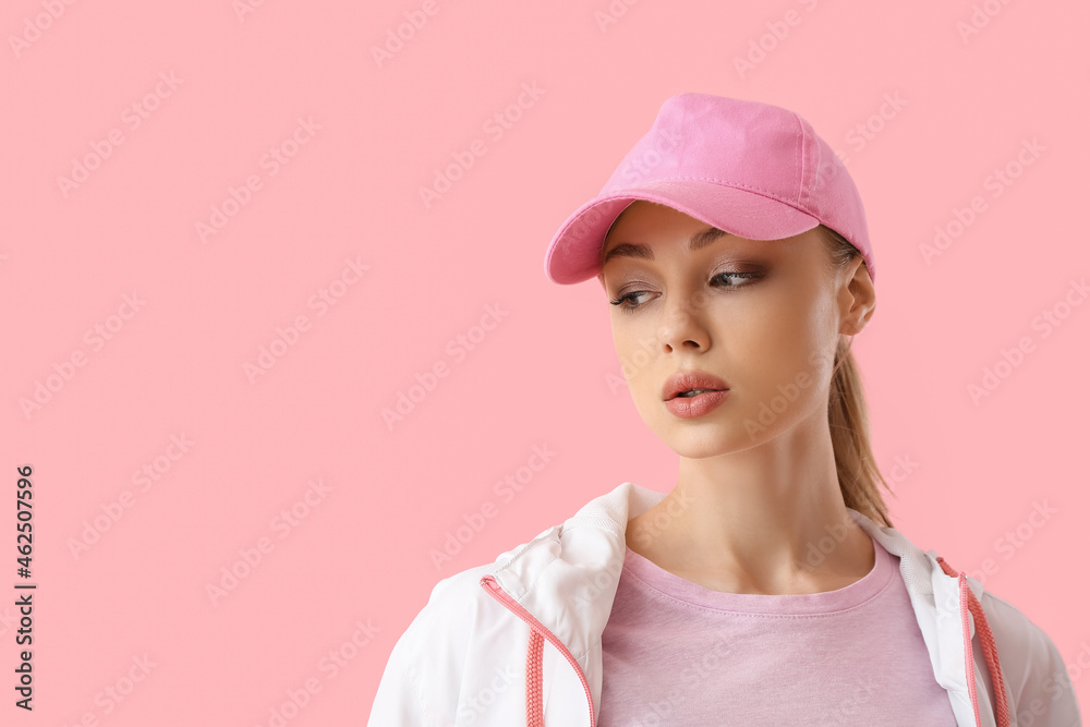 粉色背景戴棒球帽的沉思女人
