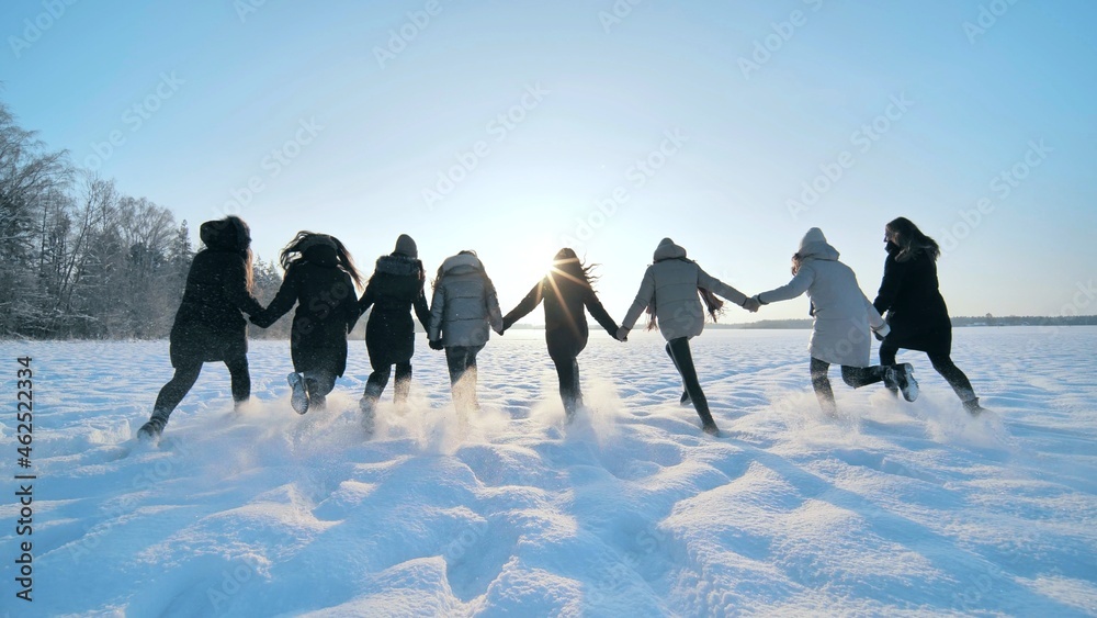 快乐的女孩们在白雪覆盖的田野上奔跑。