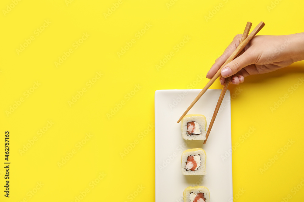 女人从彩色背景的盘子里拿美味的寿司卷，特写