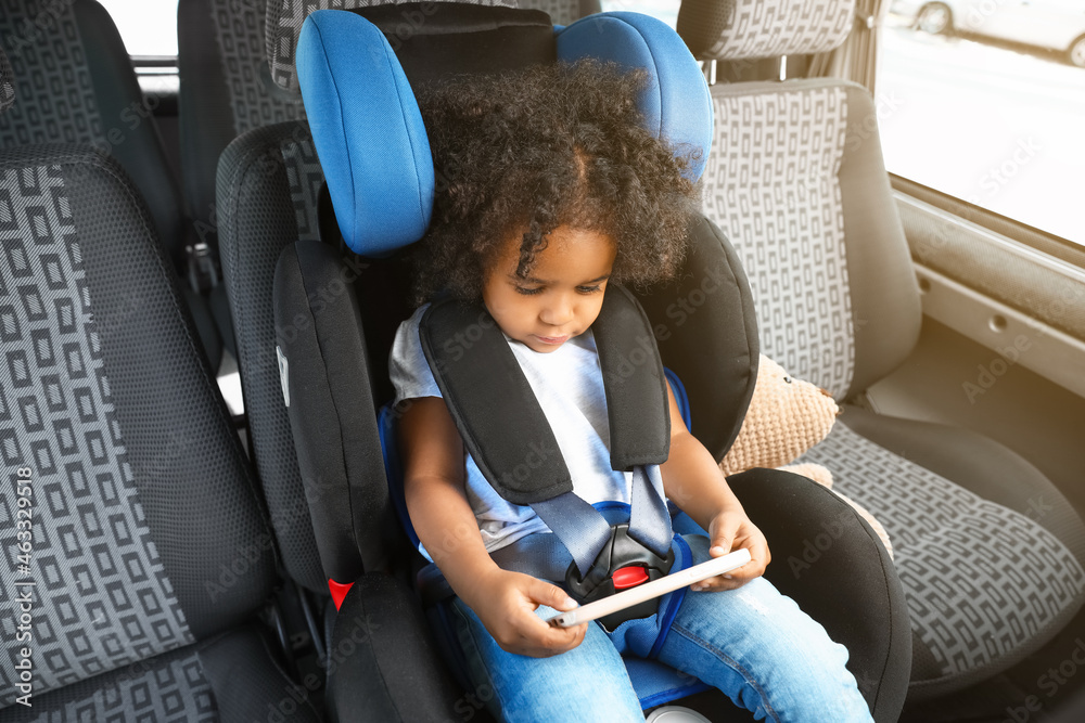 非洲裔小女孩拿着手机在汽车安全座椅上看动画片