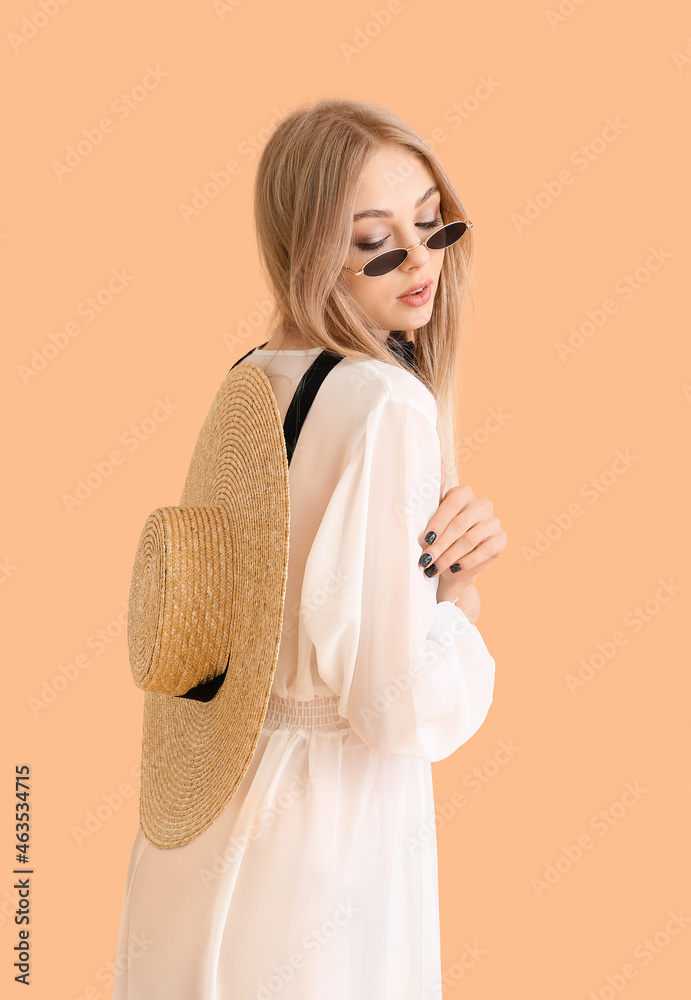Beautiful woman in sunglasses with wicker hat on color background