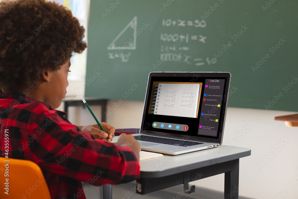 非裔美国男孩用笔记本电脑进行视频通话，课堂在屏幕上