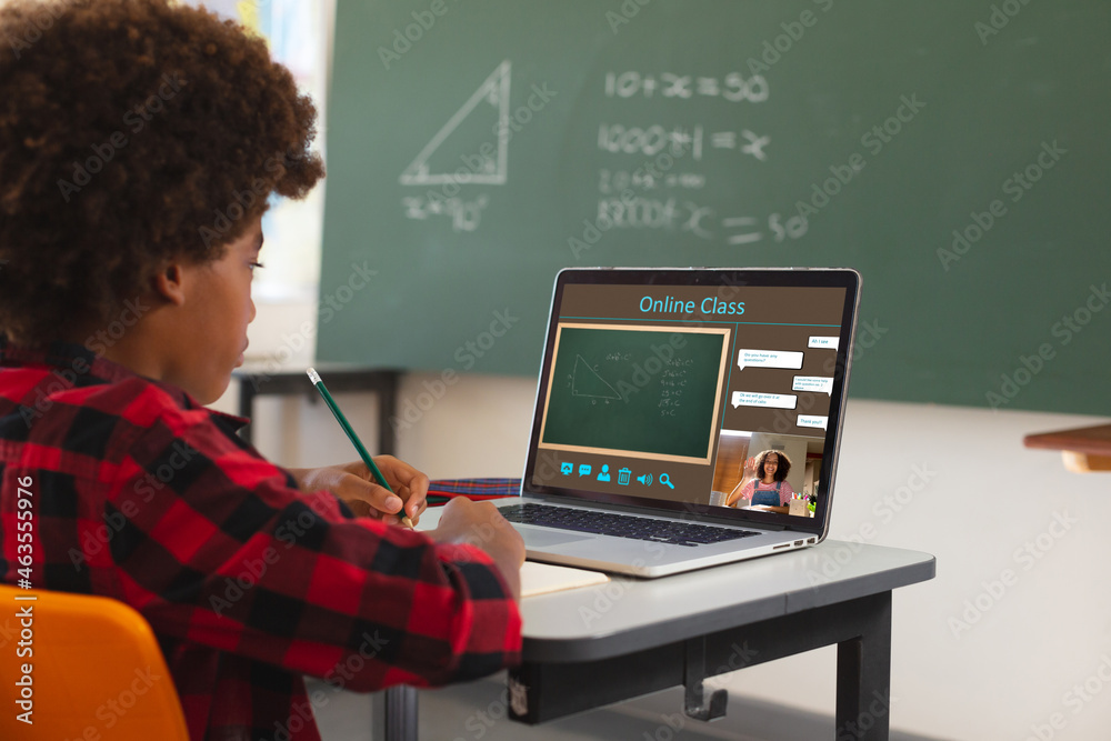 非裔美国男孩使用笔记本电脑进行视频通话，屏幕上有女老师