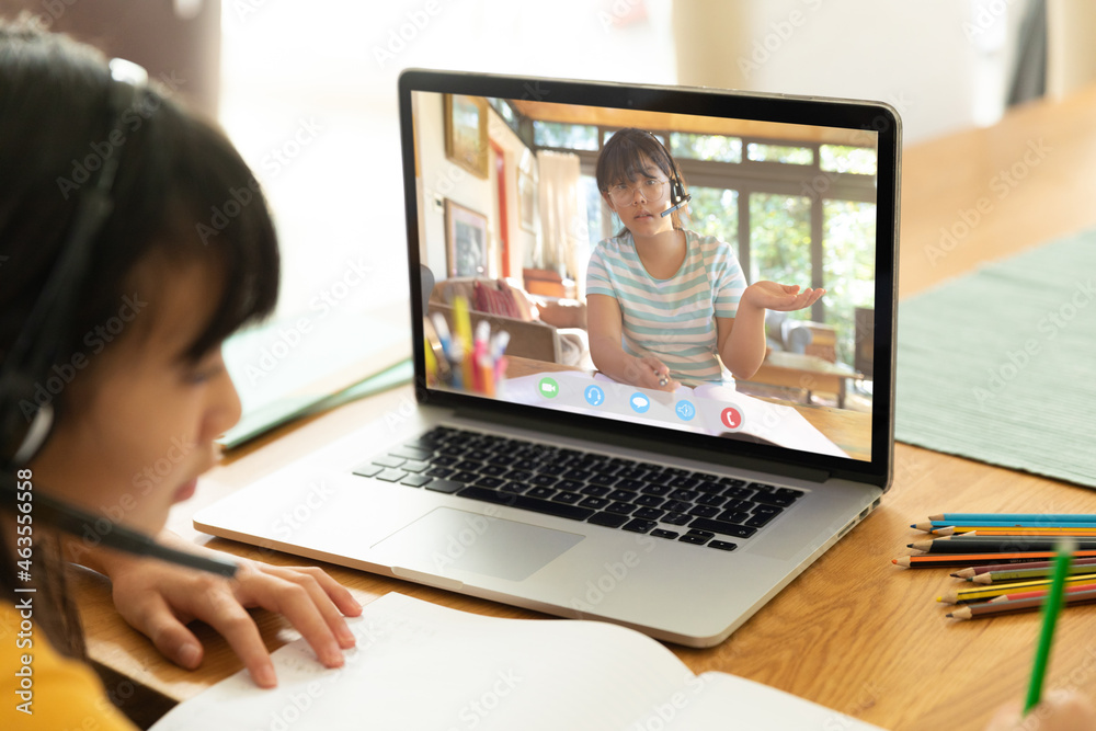亚洲女孩使用笔记本电脑进行视频通话，屏幕上有高中生