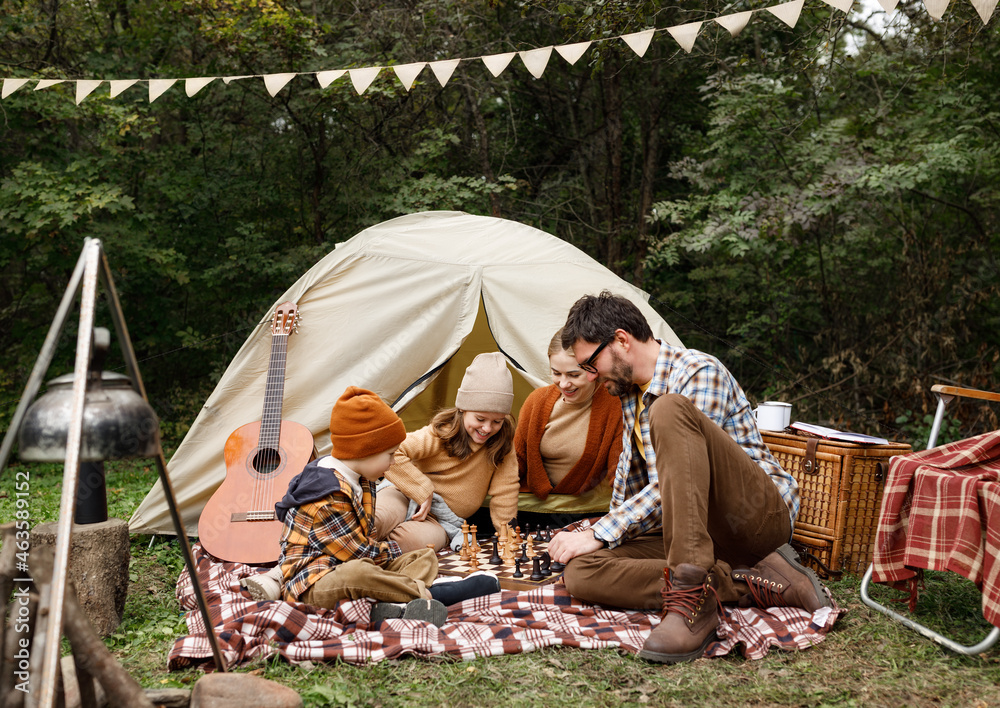 大自然露营之旅，快乐微笑的一家人在露营地下棋