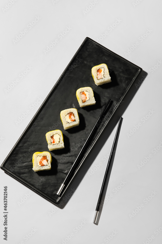 浅背景上有美味的寿司卷和筷子的盘子