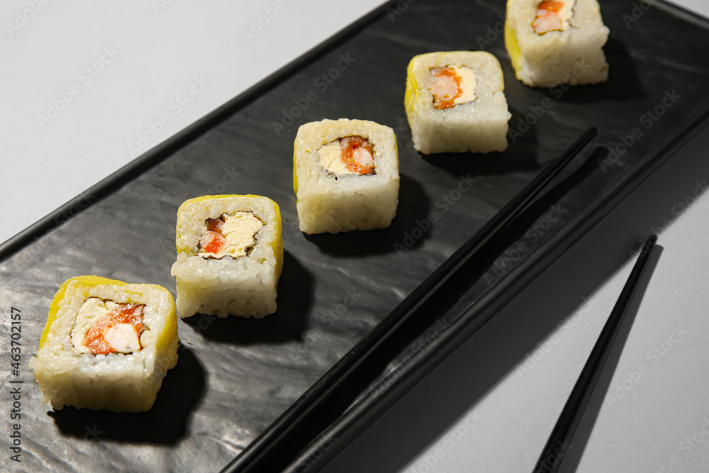 浅背景下的盘子里有美味的寿司卷和筷子，特写