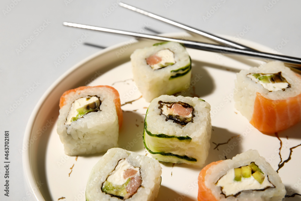 浅背景下的盘子里有美味的寿司卷和筷子，特写