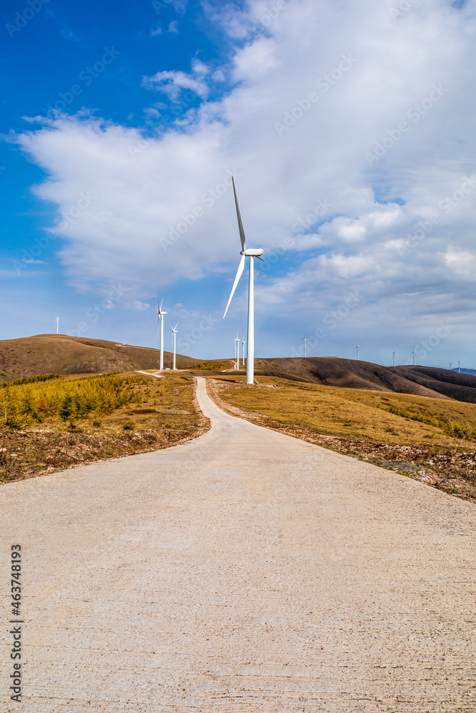 在秋季，弯曲的道路和山脉与风力涡轮机景观。