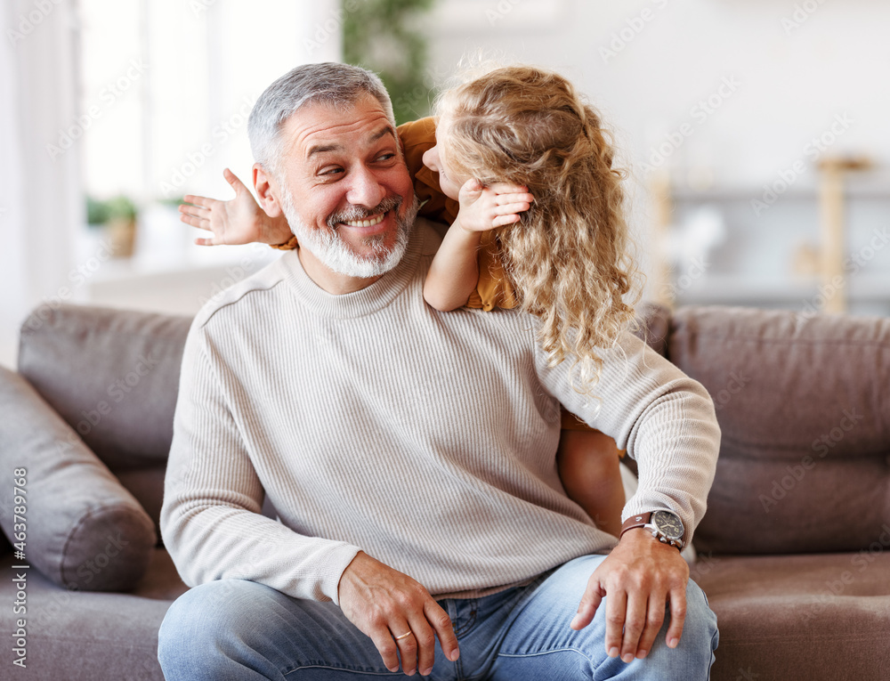 可爱的小女孩在家里一起玩耍时，用微笑的爷爷的手捂住眼睛