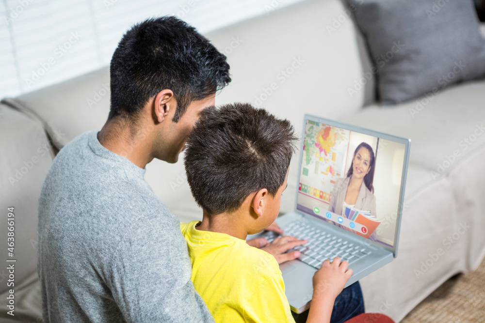 混血男孩，父亲用笔记本电脑进行视频通话，屏幕上有微笑的白人老师