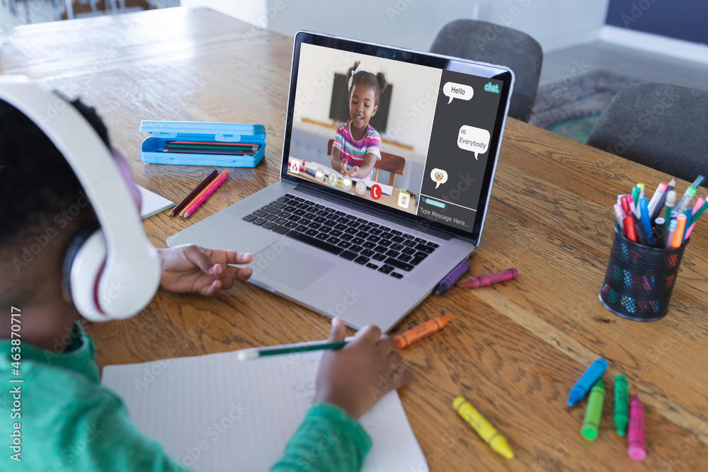 非裔美国男孩用笔记本电脑进行视频通话，屏幕上有微笑的小学生