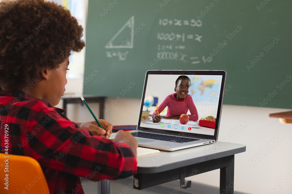 African american boy using laptop for video call, with elementary school pupil on screen