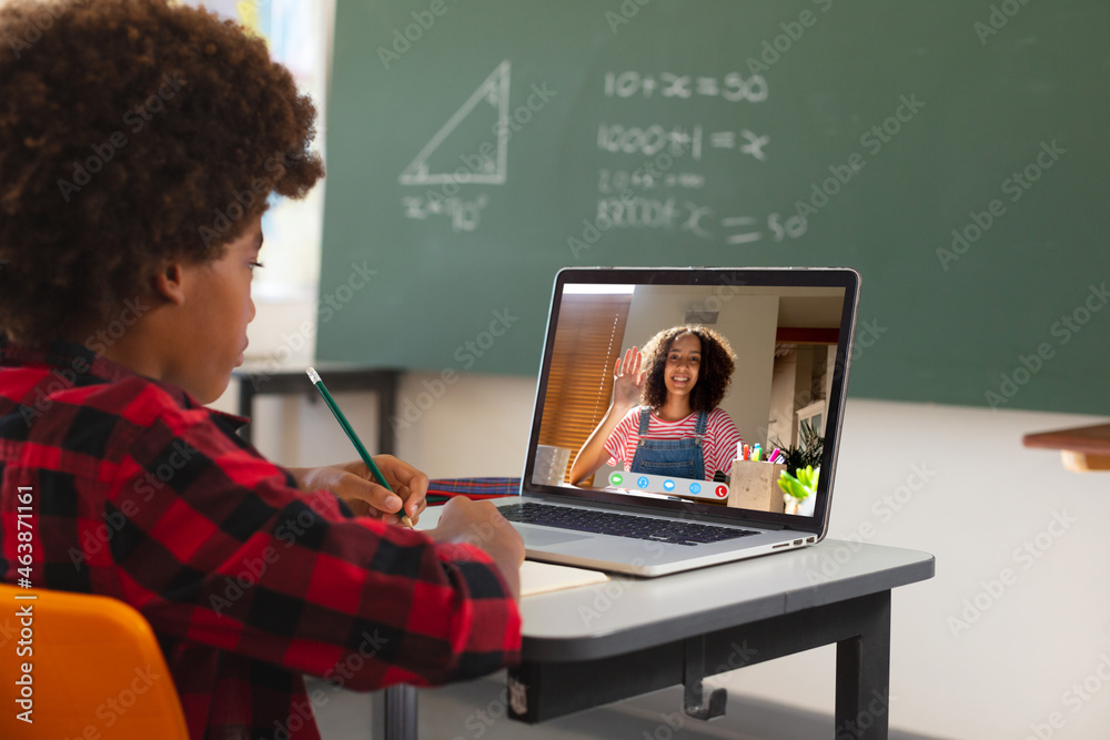 非裔美国男孩用笔记本电脑进行视频通话，屏幕上有小学生