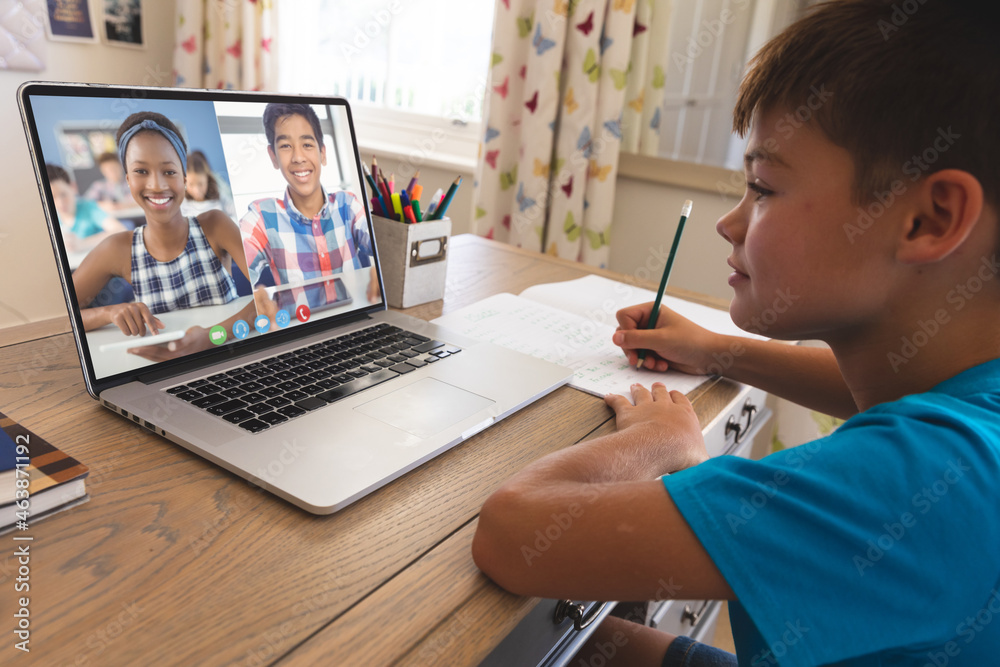 面带微笑的白人男孩使用笔记本电脑进行视频通话，屏幕上有不同的高中学生