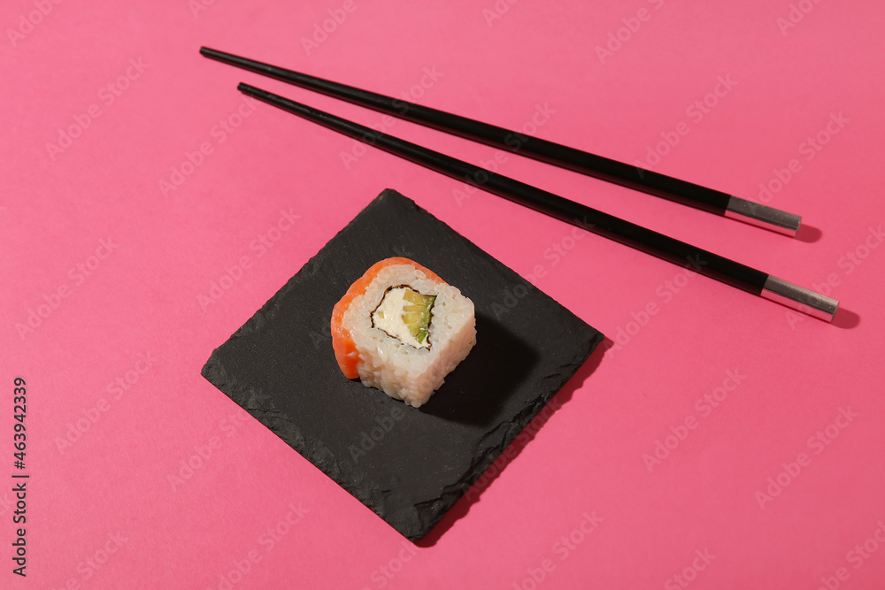 彩色背景上有美味的寿司卷和筷子的木板