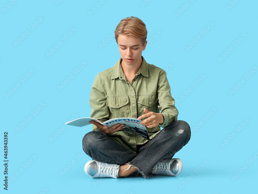 年轻女性在蓝色背景下阅读杂志