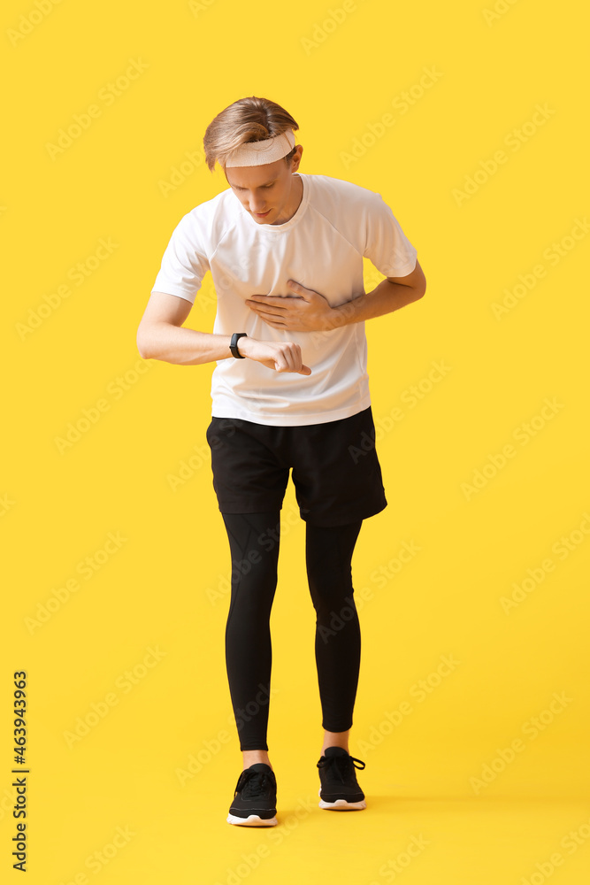 运动男跑步者在彩色背景上检查脉搏