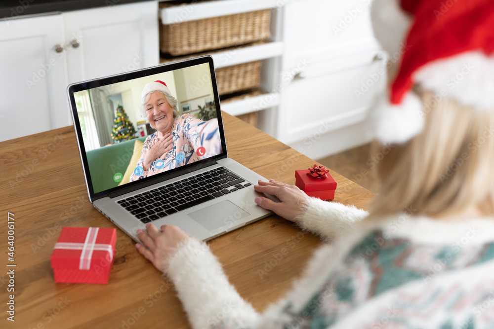 Caucasian woman in santa hat on christmas laptop video call with senior woman