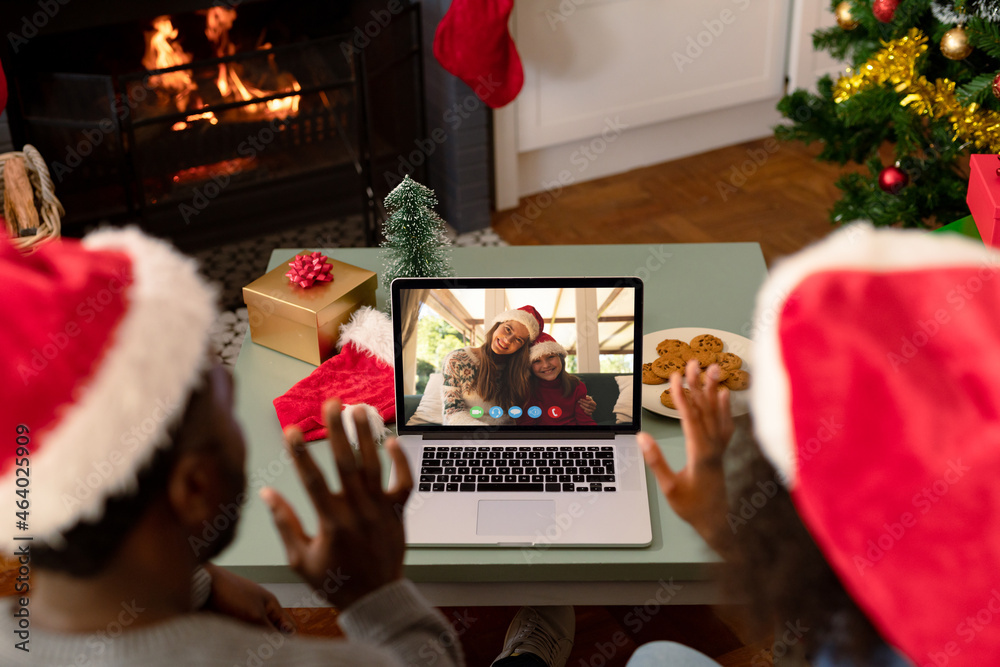 一对戴着圣诞老人帽的非裔美国夫妇在笔记本电脑上与朋友进行圣诞视频通话