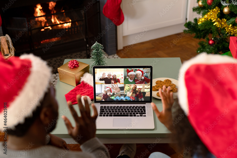一对戴着圣诞老人帽的非裔美国夫妇在笔记本电脑上与朋友进行圣诞视频通话