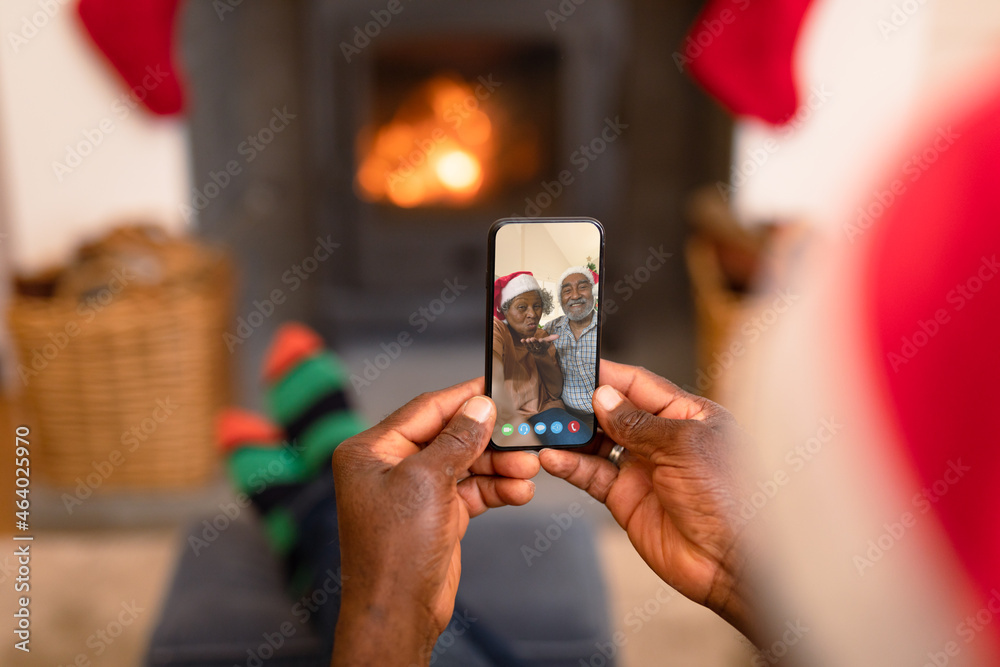 戴圣诞老人帽的非裔美国人在智能手机上与一对微笑的夫妇进行圣诞视频通话