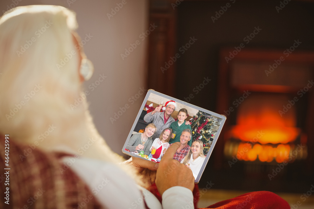 圣诞老人在圣诞平板电脑上与微笑的高加索儿童、父母和祖父母视频通话