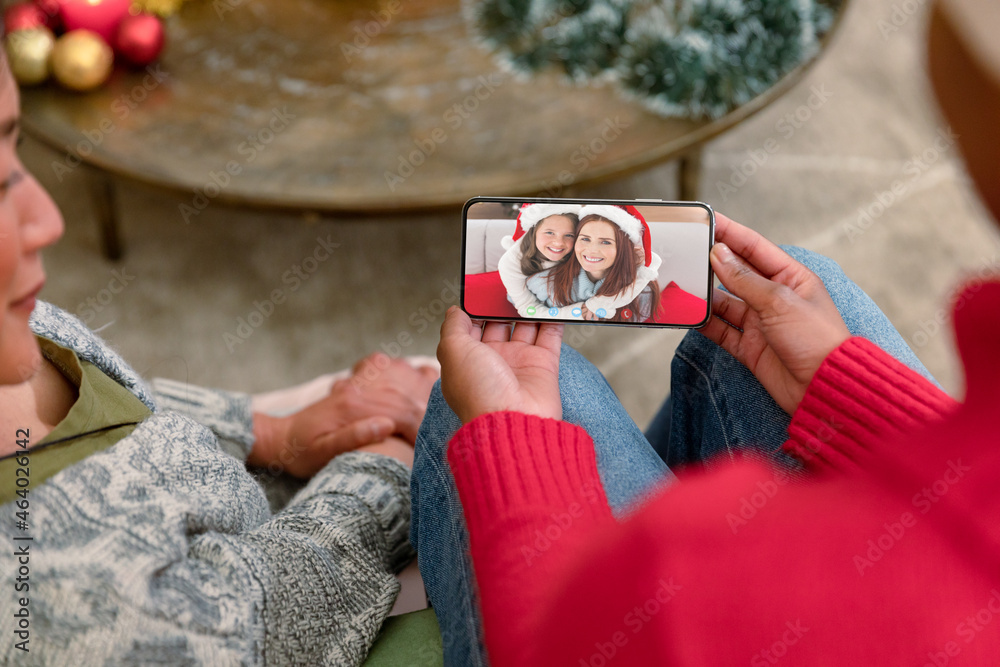 多元化夫妇与幸福的高加索母女进行智能手机圣诞视频通话