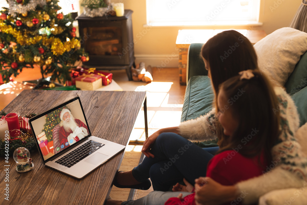 快乐的高加索母女与圣诞老人进行笔记本电脑圣诞视频通话