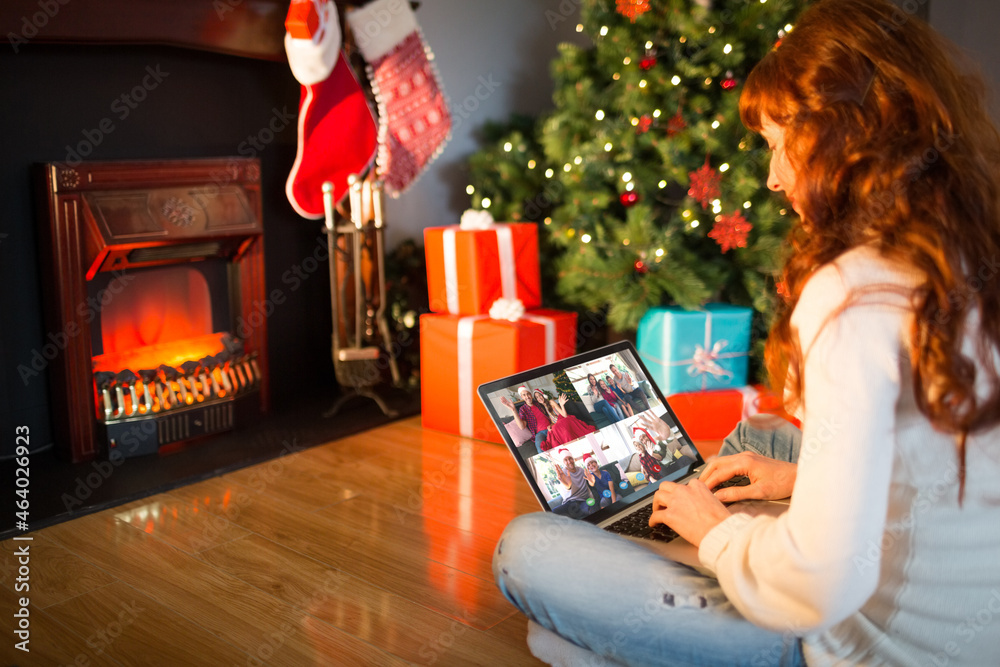 Caucasian woman on christmas tablet video call with diverse group of friends