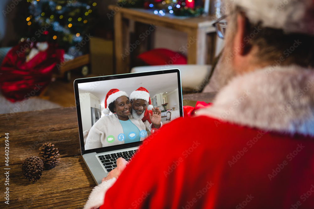 Caucasian santa claus on christmas laptop video call with african american couple