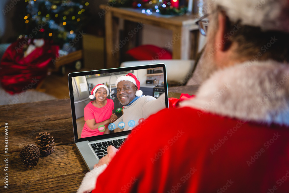 高加索圣诞老人在圣诞笔记本电脑上与非裔美国夫妇视频通话