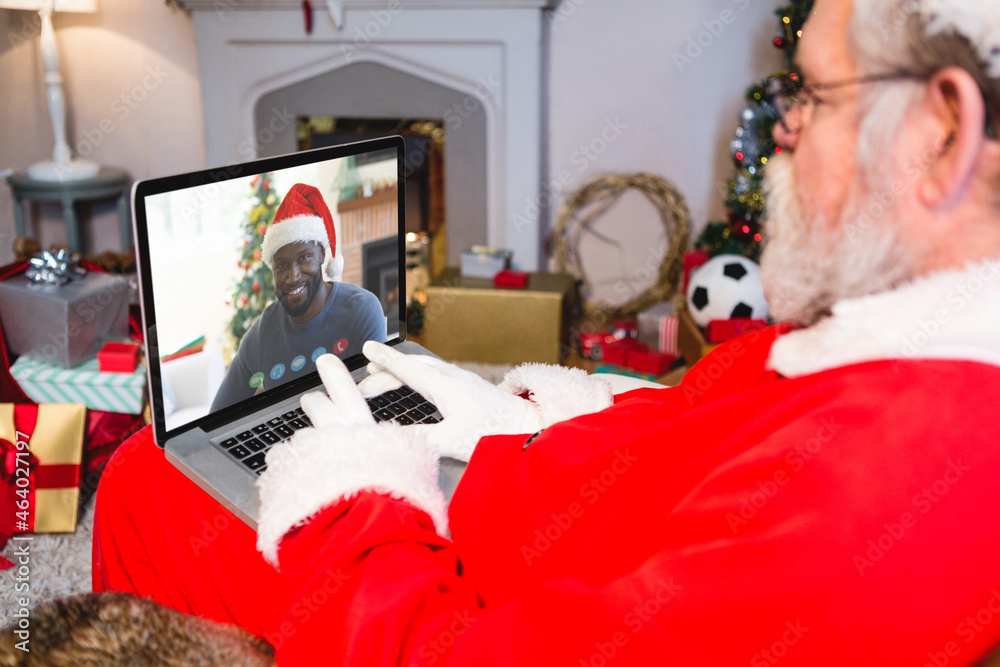 白人圣诞老人在圣诞笔记本电脑上与非洲裔美国人视频通话