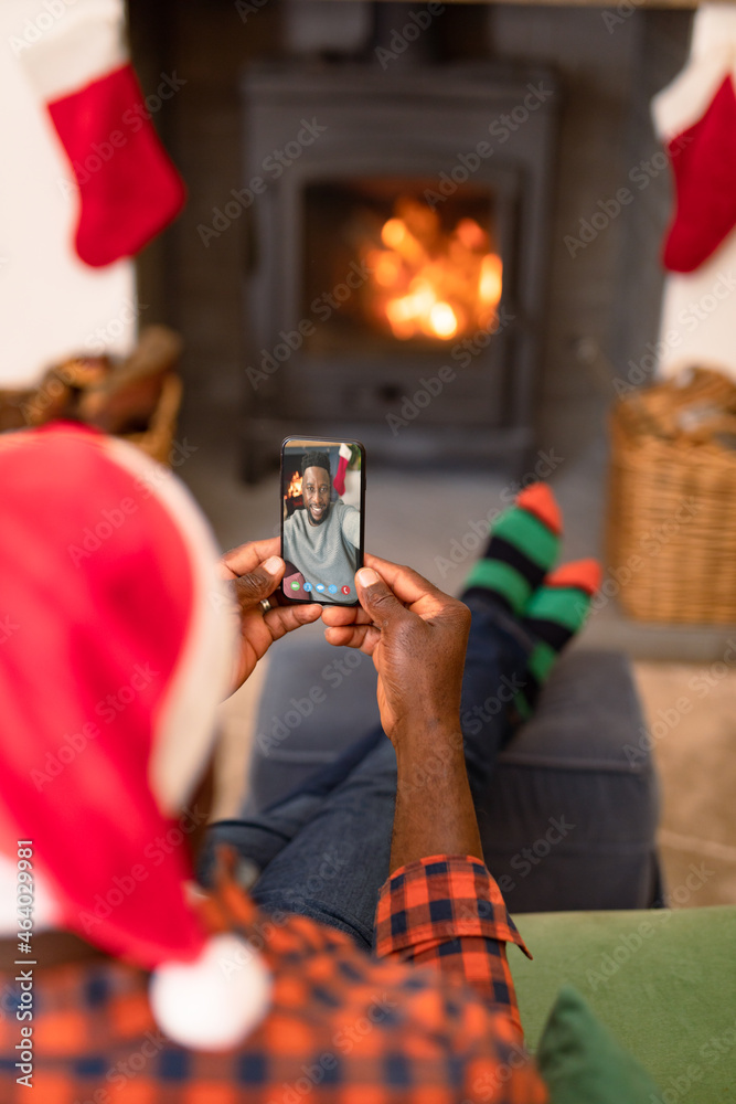 戴圣诞老人帽的非裔美国人与男性朋友在智能手机上视频通话