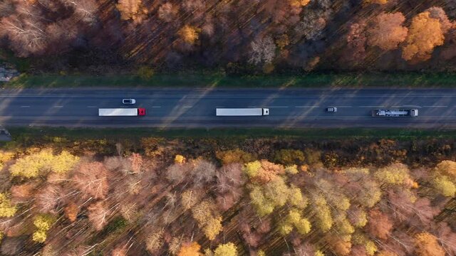 Freight container truck hauling and delivering cargo across a country. Aerial shot of trucks with cargo trailer driving on road and transporting goods. High quality. 4k footage.