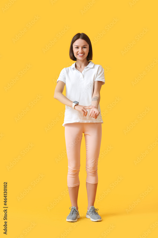 Sporty female runner checking pulse on color background