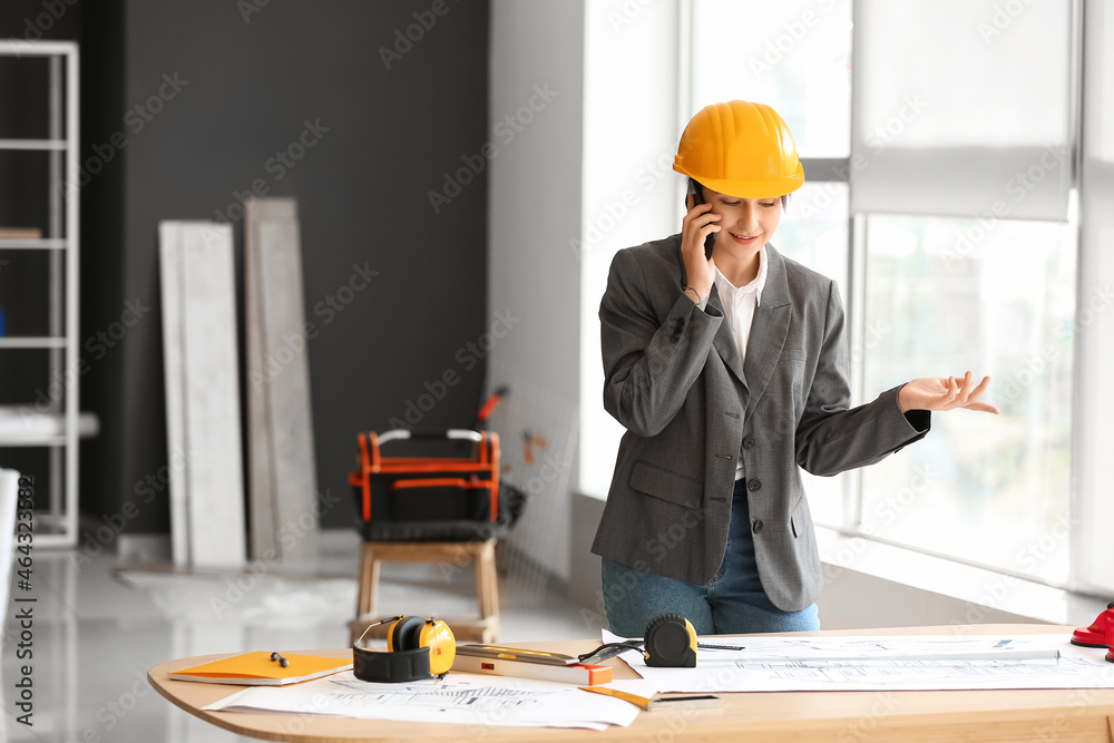 女工业工程师在办公室桌子旁用手机聊天