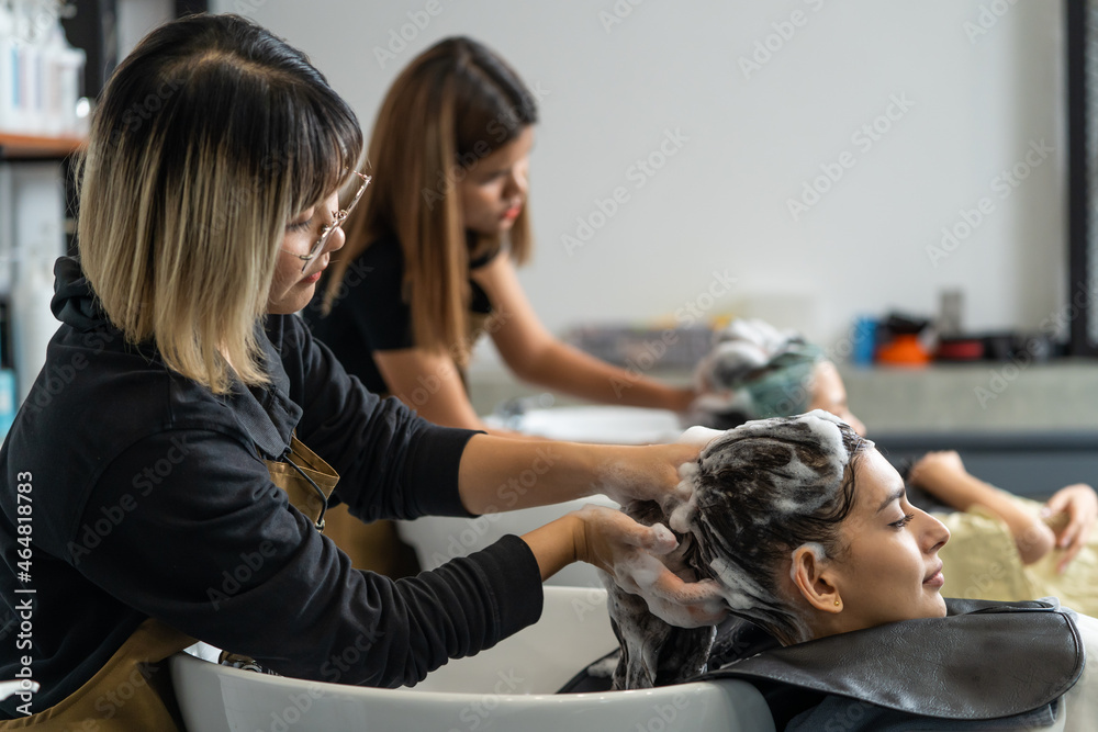 亚洲专业理发师为年轻顾客按摩和洗头。