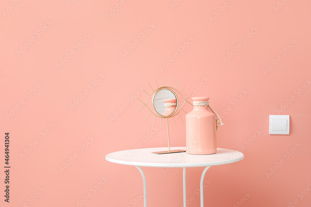 粉色墙壁附近有镜子和花瓶的桌子