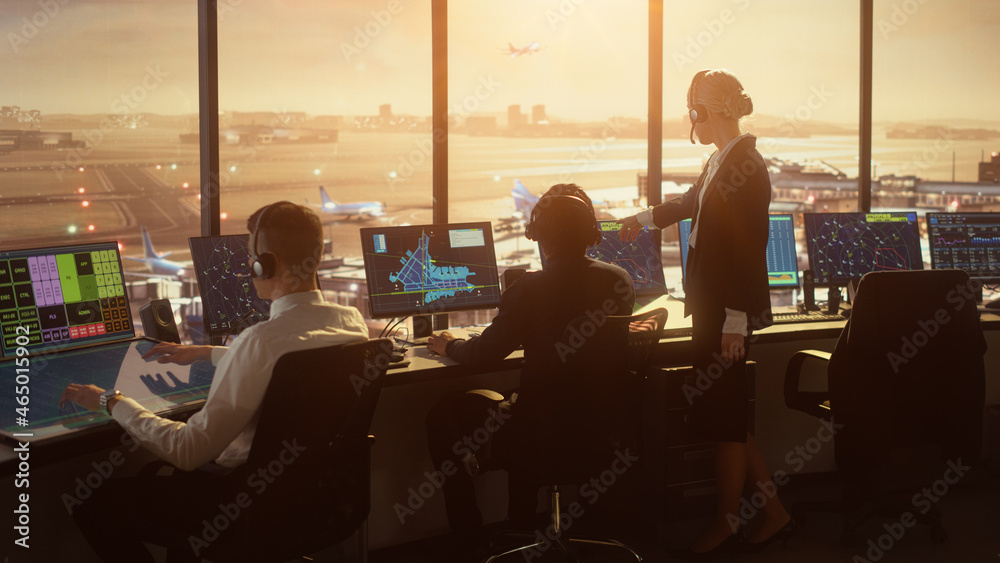 多样化的空中交通管制团队在日落的现代机场大楼里工作。办公室里挤满了人