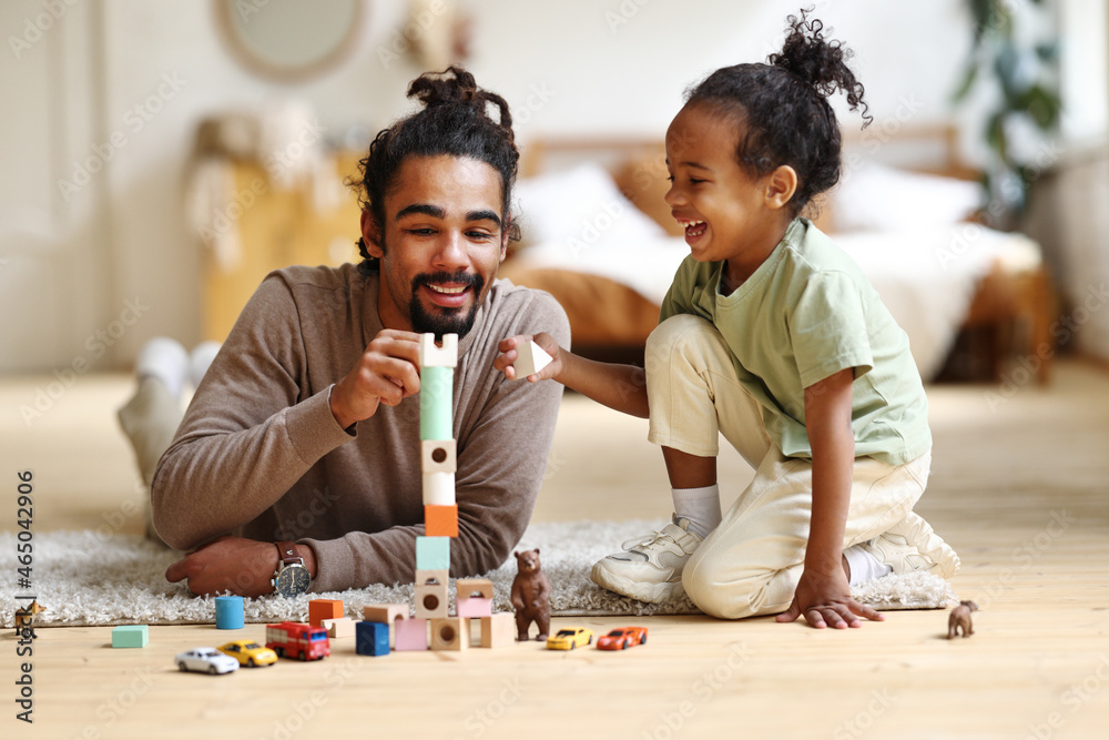 快乐的非裔美国人家庭父亲和孩子儿子在家一起玩玩具时大笑