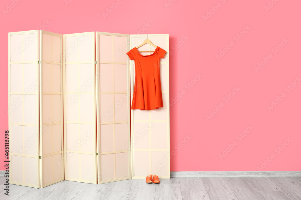 粉色墙壁附近的红色连衣裙和鞋子的轻型折叠屏幕