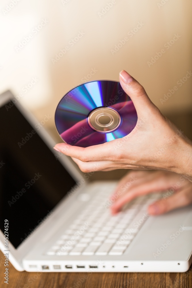 Hand Holding CD , DVD on Laptop