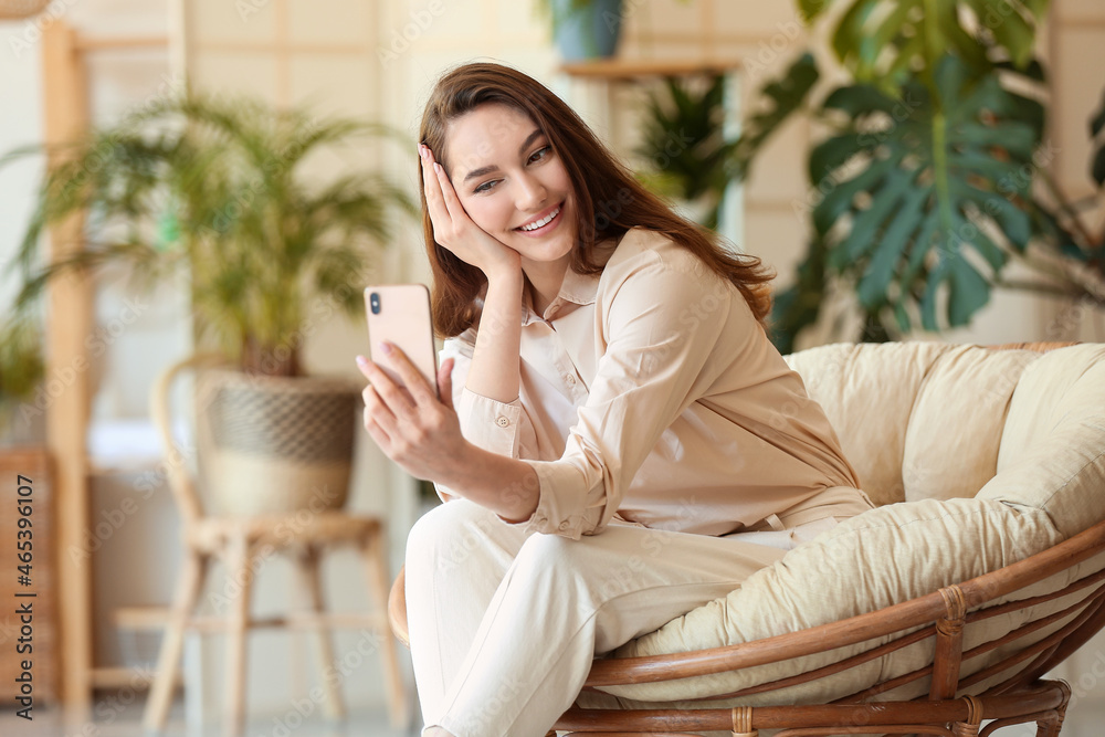 Beautiful smiling woman taking selfie in armchair